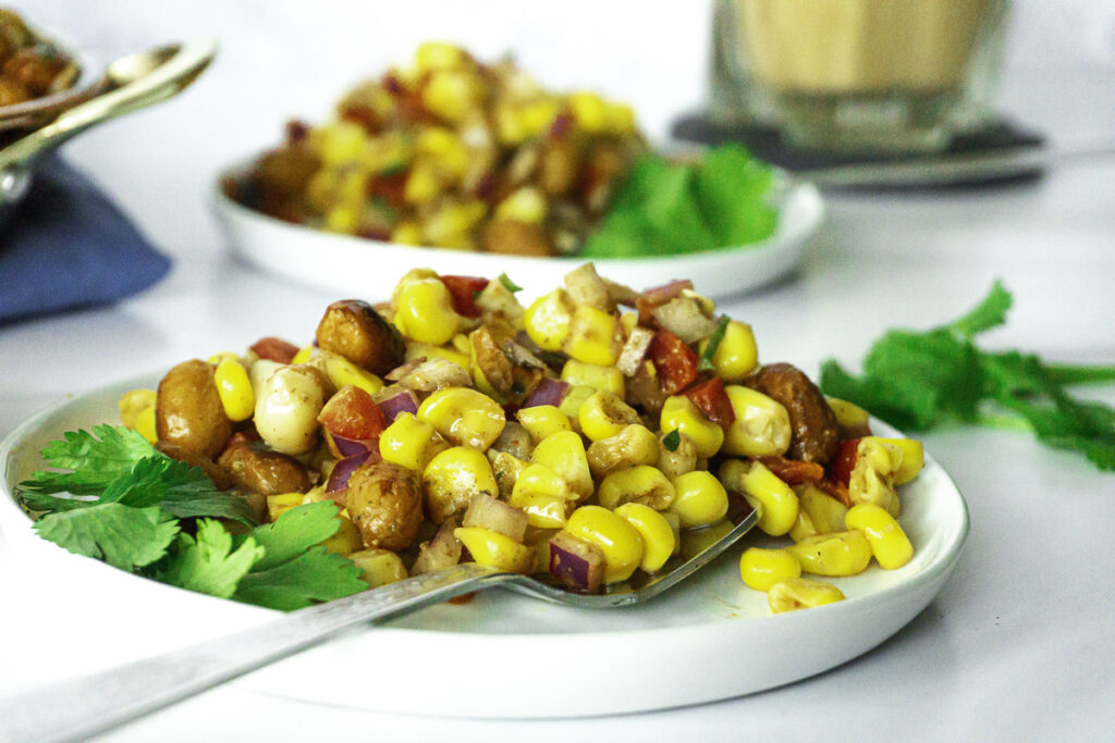 Corn chaat with peanuts, bell peppers, onions, masala, and topped with cilantro